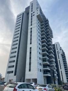 een hoog gebouw met auto's geparkeerd op een parkeerplaats bij Beauty apartment 3 rooms wi-fi in Netanya