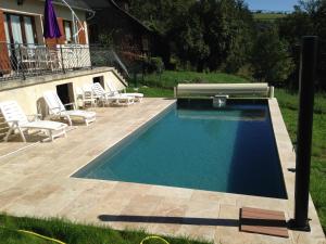a swimming pool in a yard with chairs next to a house at Sécadou Castanial in Cassaniouze