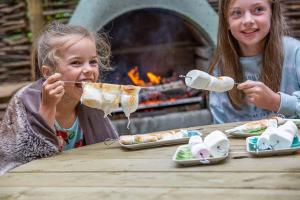 two young girls eating food at a table with a fireplace at HAYNE BARN ESTATE - 2 Luxury heated Yurts - private hot tub- private bathroom and kitchen in Hythe