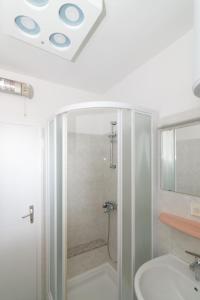 ein weißes Bad mit einer Dusche und einem Waschbecken in der Unterkunft Apartments Jasna 2 in Novigrad Istria