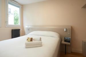 a bedroom with a white bed and a television at Hotel Le Petit Duquesne in Nantes