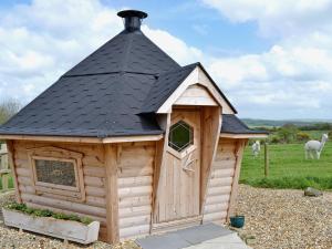 a large wooden dog house with a black roof at The Granary- Osc in Penbryn