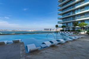 Una piscina con tumbonas y un edificio. en Vogue Fascinating Beachfront One Bedroom Apartment with Balcony and Palm Views & Private Beach with full Amenities, en Dubái