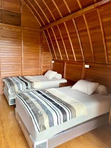 two beds in a room with wooden walls at Vila Kopi Ciwidey in Ciwidey