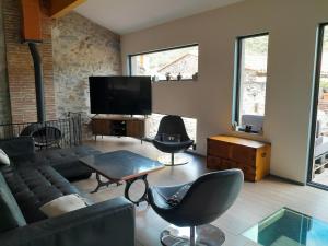 a living room with a couch and a flat screen tv at Loft vue montagne in Rigarda