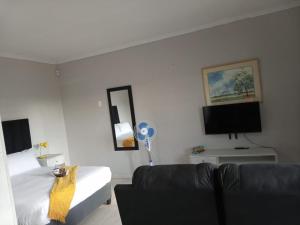 um quarto com uma cama, um sofá e uma televisão em Bella's self contained daily accommodation em Meyerton