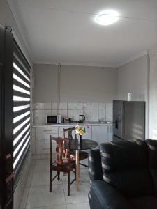 a living room with a table and chairs and a kitchen at Bella's self contained daily accommodation in Meyerton