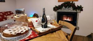 una mesa con una tarta y copas de vino y una chimenea en Baita Relais La Cesarina, en Vico Canavese