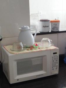 a white microwave with a tea pot on top of it at Apartamento de luxo com 2 quartos, sala com sacada, cozinha área de serviço e 1 banheiro social. in Ipatinga
