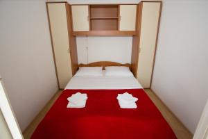 - un lit avec 2 oreillers blancs et une couverture rouge dans l'établissement Beach Studio Apartment Ivana, à Kaštela