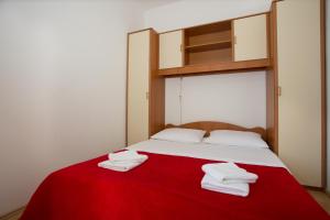 - un lit avec une couverture rouge et des serviettes blanches dans l'établissement Beach Studio Apartment Ivana, à Kaštela