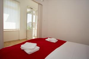 - un lit rouge et blanc avec des serviettes blanches dans l'établissement Beach Studio Apartment Ivana, à Kaštela