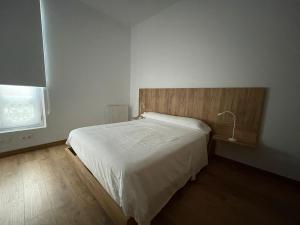 1 dormitorio con cama blanca y cabecero de madera en Apartamentos Turísticos Las Ánimas Comillas, en Comillas