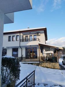 a house with snow on the ground in front of it at Бадевски рай-къща Надежда in Badewzi