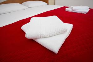 - deux serviettes blanches assises sur un lit rouge dans l'établissement Beach Studio Apartment Ivana, à Kaštela