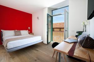 una camera da letto con una parete rossa, un letto e una scrivania di YourHome - Lidia Rooms & Suites a Sorrento