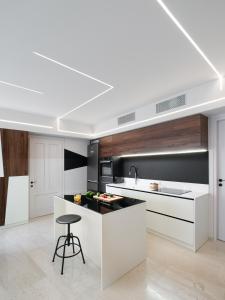 een keuken met witte kasten en een zwart eiland met een kruk bij The H Experience - Stylish 2BD apt with balcony in Heraklion center in Heraklion