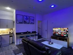 een woonkamer met een bank en een keuken met paarse muren bij Luxe Loft Living: A Home Away From Home in Wibsey