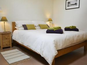 a bedroom with a large white bed with towels on it at Meillion Cottage in Letterston