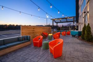 a patio with a couch and orange chairs on a building at Aloft Lawrenceville Sugarloaf in Lawrenceville