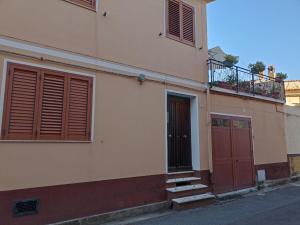 サン・ヴィートにあるAppartamento Ginepro Sardegnaの赤いドアとバルコニー付きの建物