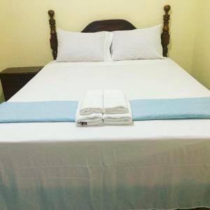 a bed with a white towel laying on it at Royal Vybez Vacation Homes in Spanish Town