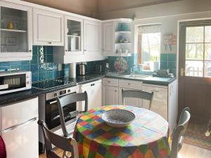 uma cozinha com armários brancos e uma mesa com uma tigela em Heron em Welney