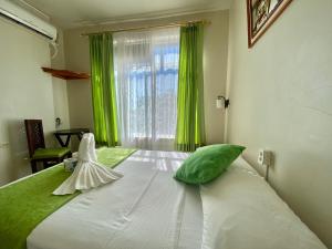 1 dormitorio con 1 cama con cortinas verdes y ventana en El Rincón de George en Puerto Villamil