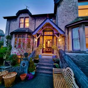 une maison en briques avec un banc devant elle dans l'établissement Grange Boutique Hotel, à Grange-over-Sands