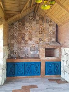 cocina con armarios azules y pared de piedra en Cabaña Agapanto Azul en Constanza