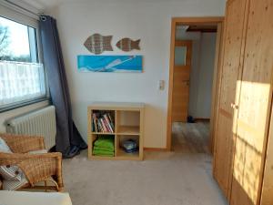 ein Wohnzimmer mit einem Bücherregal und einem Fenster in der Unterkunft Voslapper Seeluft in Wilhelmshaven