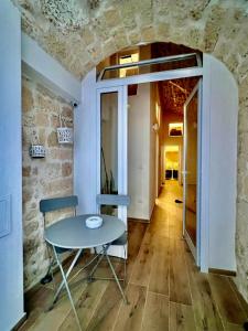 uma mesa e cadeiras num quarto com uma parede de pedra em La Maison Arco Boccolicchio em Manfredonia
