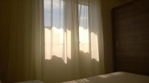 um quarto com uma janela com cortinas brancas e uma cama em Rooms & Apartments Blue Beach em Vodice