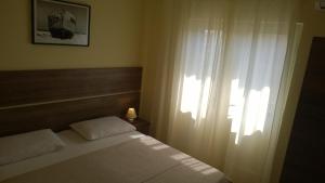 a bedroom with a white bed and a window at Rooms & Apartments Blue Beach in Vodice