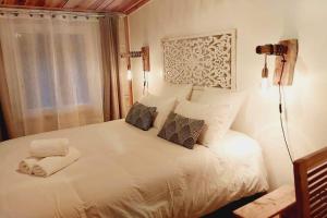 a bedroom with a large white bed with two pillows at Le Margousier in Cilaos