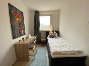 een slaapkamer met een bed, een bureau en een raam bij Blue Chili 16 Familienwohnung nahe Uniklinik - Boxspringbett Balkon Wlan in Maagdenburg