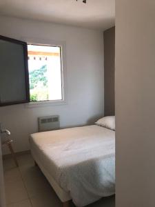 a white bedroom with a bed and a window at Appartement 1 chambre vue mer et grande terrasse in Cavalaire-sur-Mer
