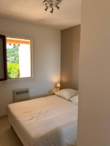 a white bedroom with a bed and a window at Appartement 1 chambre vue mer et grande terrasse in Cavalaire-sur-Mer