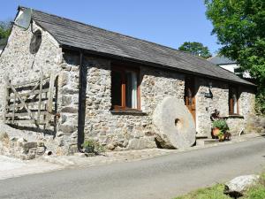 a stone building with a large window and a large stone letter at The Smithy in Brentor