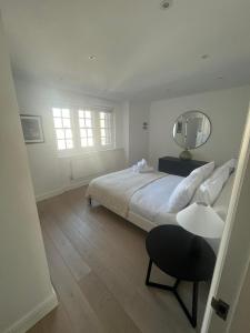 a white bedroom with a large bed and a mirror at Stunning Marylebone apartment in London