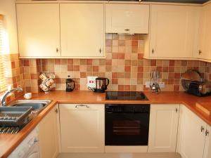 una cucina con armadietti bianchi e lavastoviglie nera di Brundholme Glen a Keswick