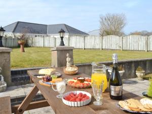 a picnic table with food and a bottle of wine at Meadowcroft in Llanllwchaiarn