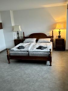 een slaapkamer met een houten bed en 2 nachtkastjes bij Gîte des Hurlevents in Bourglinster