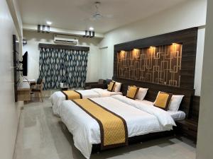 a bedroom with two beds and a desk in it at Hotel Orange in Vapi