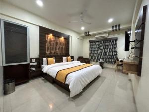 a bedroom with a large bed and a television at Hotel Orange in Vapi
