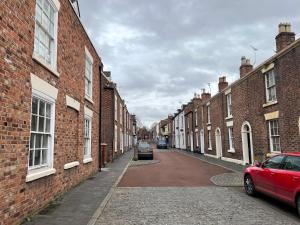 an alley with brick buildings and a red car parked on the street at Chester Stays - Beautiful loft apartment with parking in Chester