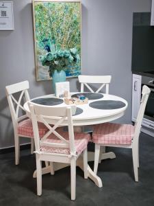 uma mesa de jantar branca e cadeiras com um quadro em Traian Apartment - Cluj em Cluj-Napoca