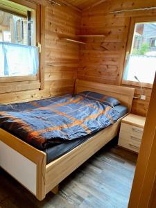 a bed in a wooden cabin with a window at Ferienhaus Nr 6, Typ A, Feriendorf Jägerpark, Bayerischer Wald in Viechtach