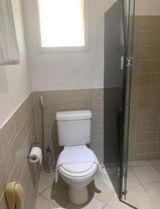 a bathroom with a toilet and a window and a shower at Bouganville Hotel in Beberibe