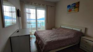 een kleine slaapkamer met een bed en een raam bij Sea Front Apartment in Vlorë